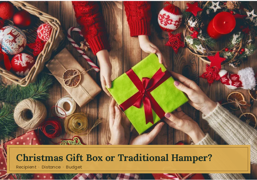 Hands passing a green wrapped Christmas gift over a festive wooden table with text "Christmas Gift Box or Traditional Hamper?".