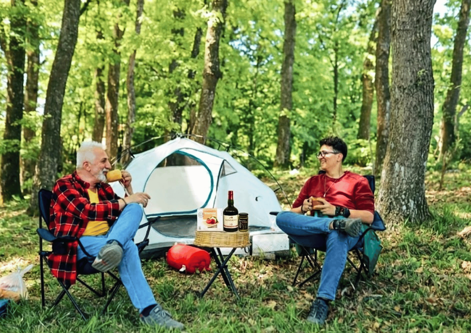 A happy senior father and adult son clink glasses together outdoors, celebrating Father's Day.