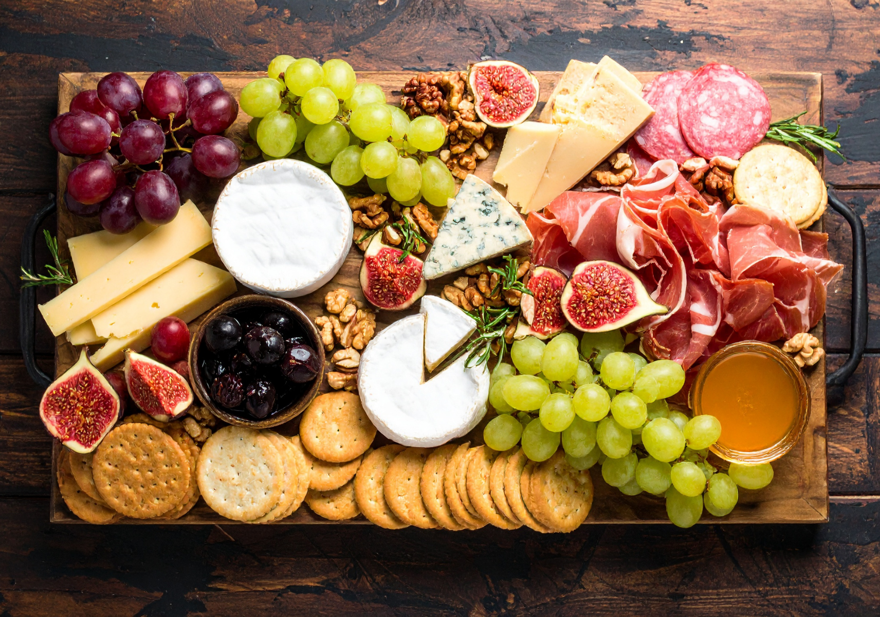 Gourmet gift basket ideas: assorted cheeses, cured meats, figs, walnuts, crackers, and honey.