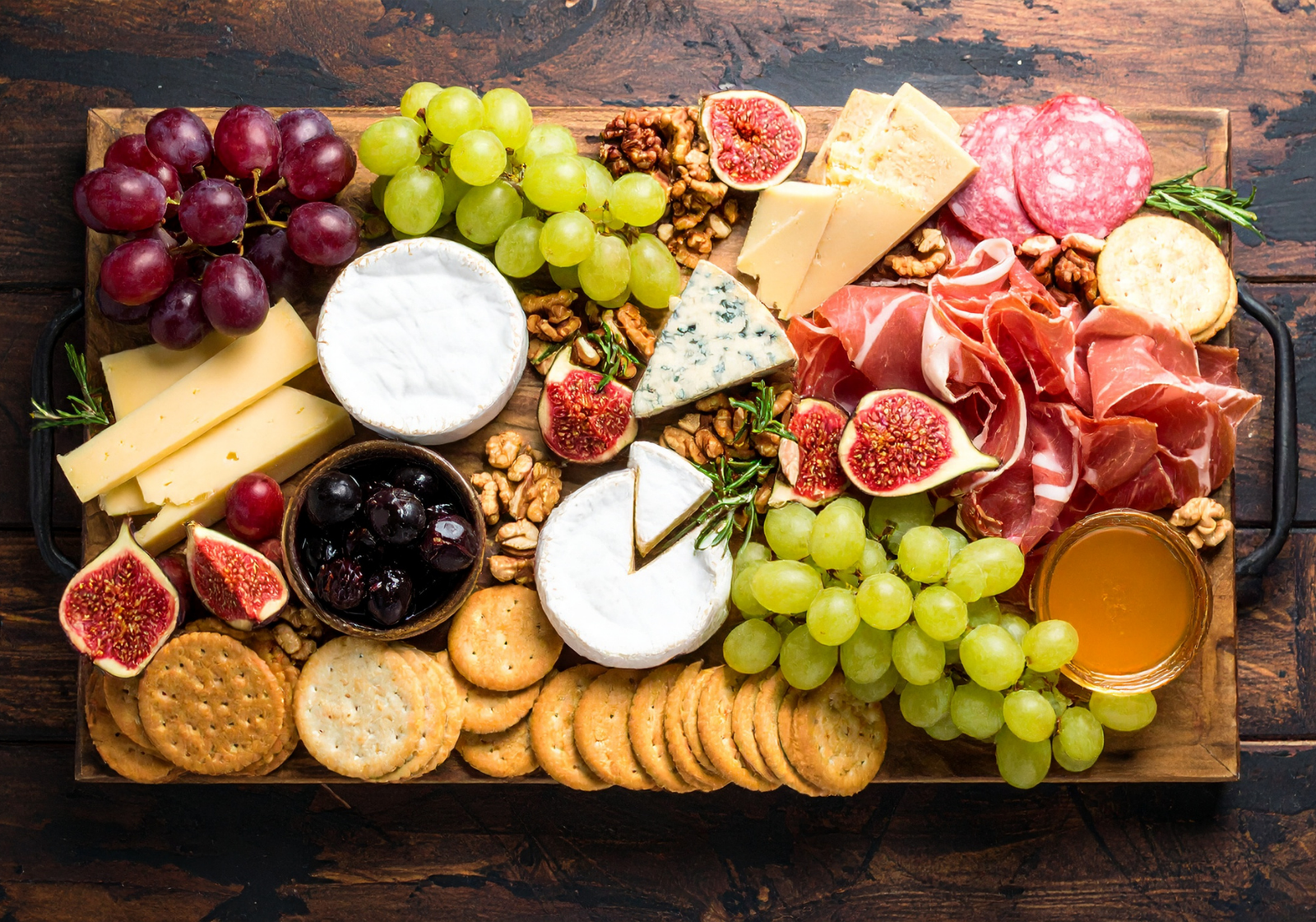 Gourmet gift basket ideas: assorted cheeses, cured meats, figs, walnuts, crackers, and honey.