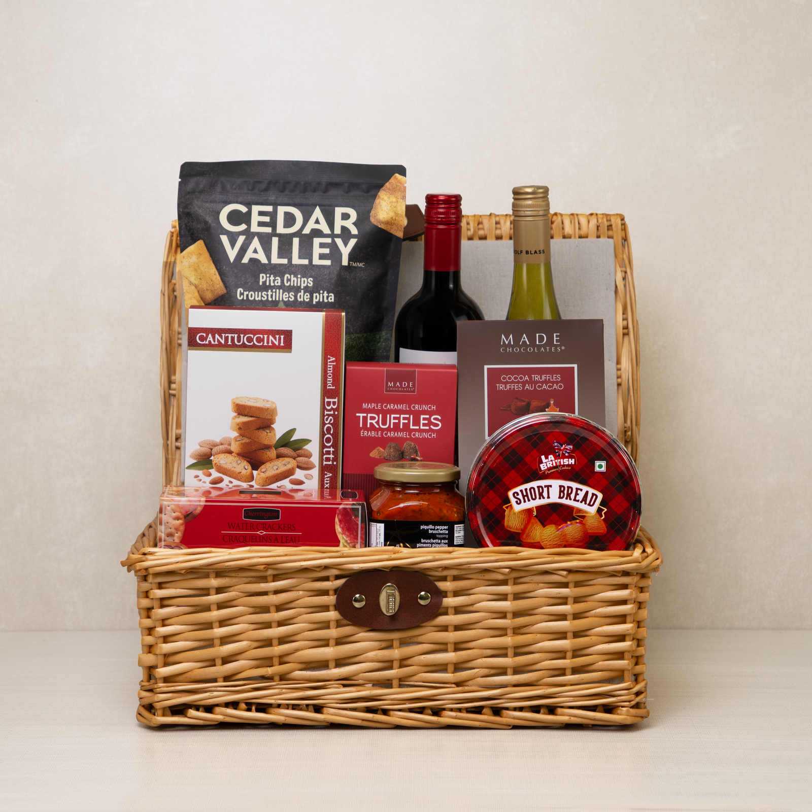 Savoury Treats Gift Basket: red and white wine, Cedar Valley pita chips, Made truffles and shortbread in a wicker hamper
