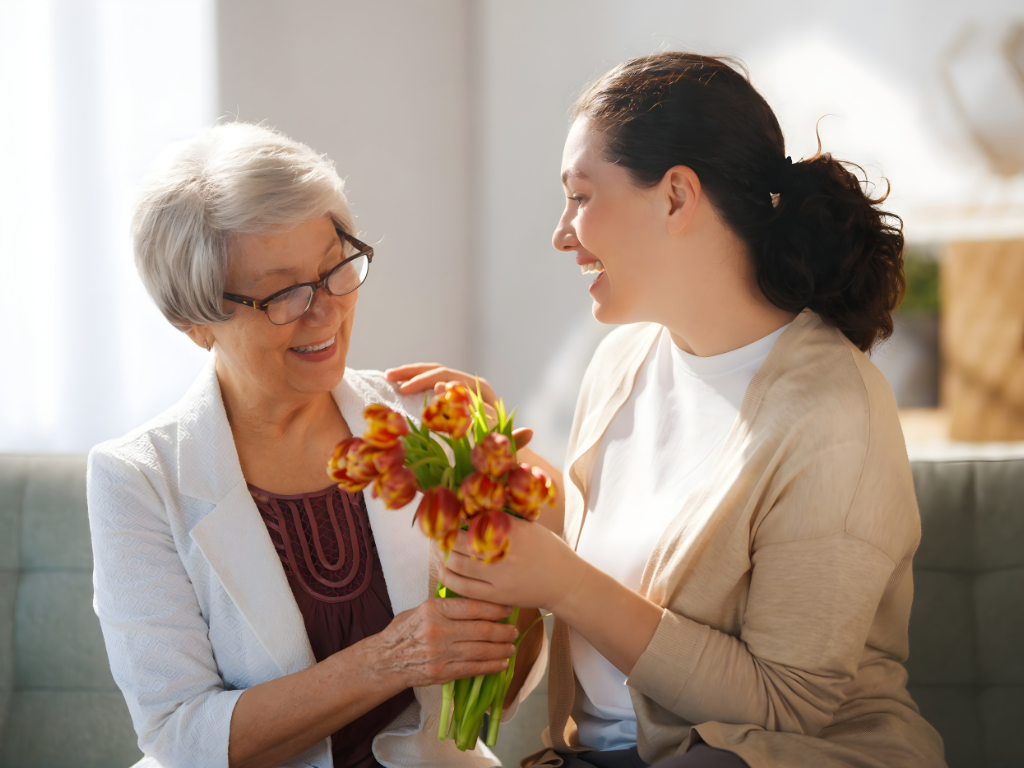 A daughter surprising her happy mother with a fresh floral bouquet for Mother's Day.