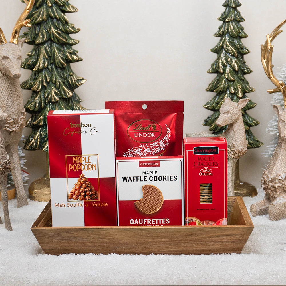 Merry Maple Basket with Bonbon maple popcorn, a Lindt Lindor pouch, maple waffle cookies and water crackers in a wooden tray