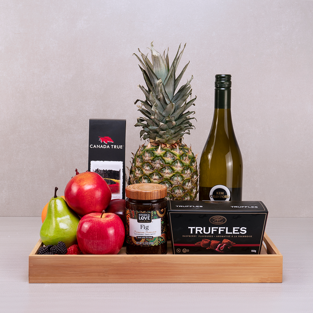 Warm Wishes Sympathy Basket with Kim Crawford white wine, a whole pineapple, apples, fig preserve and raspberry truffles