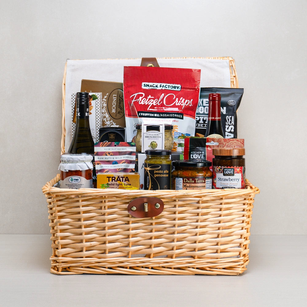 All-in-One Family Celebration Basket with white and red wine, Lindt Lindor, Pretzel Crisps and pesto in a wicker hamper
