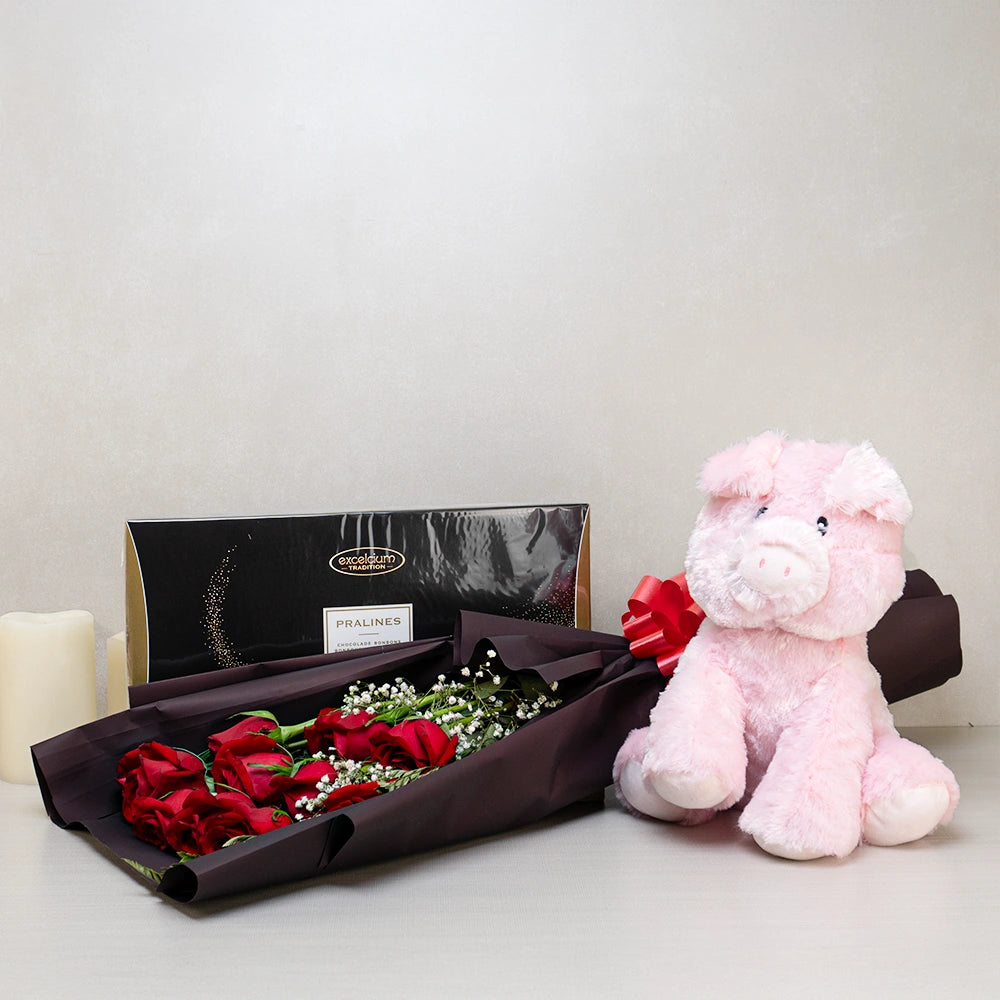 Romantic Whispers Gift Basket with a pink plush pig, red roses wrapped with baby's breath and Excelcium Belgian pralines