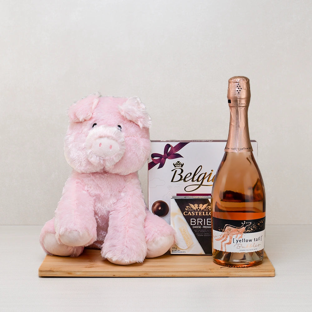 Love at First Bite Basket with a pink plush pig, Yellow Tail sparkling rosé, Belgian pralines and Castello brie on bamboo
