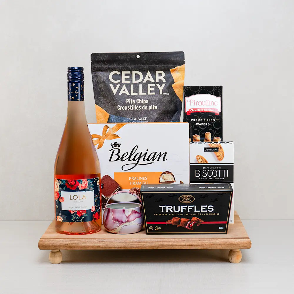 Mom’s Sweet Escape Gift Basket with LOLA rosé, a lavender candle, tiramisu pralines and raspberry truffles on a footed board