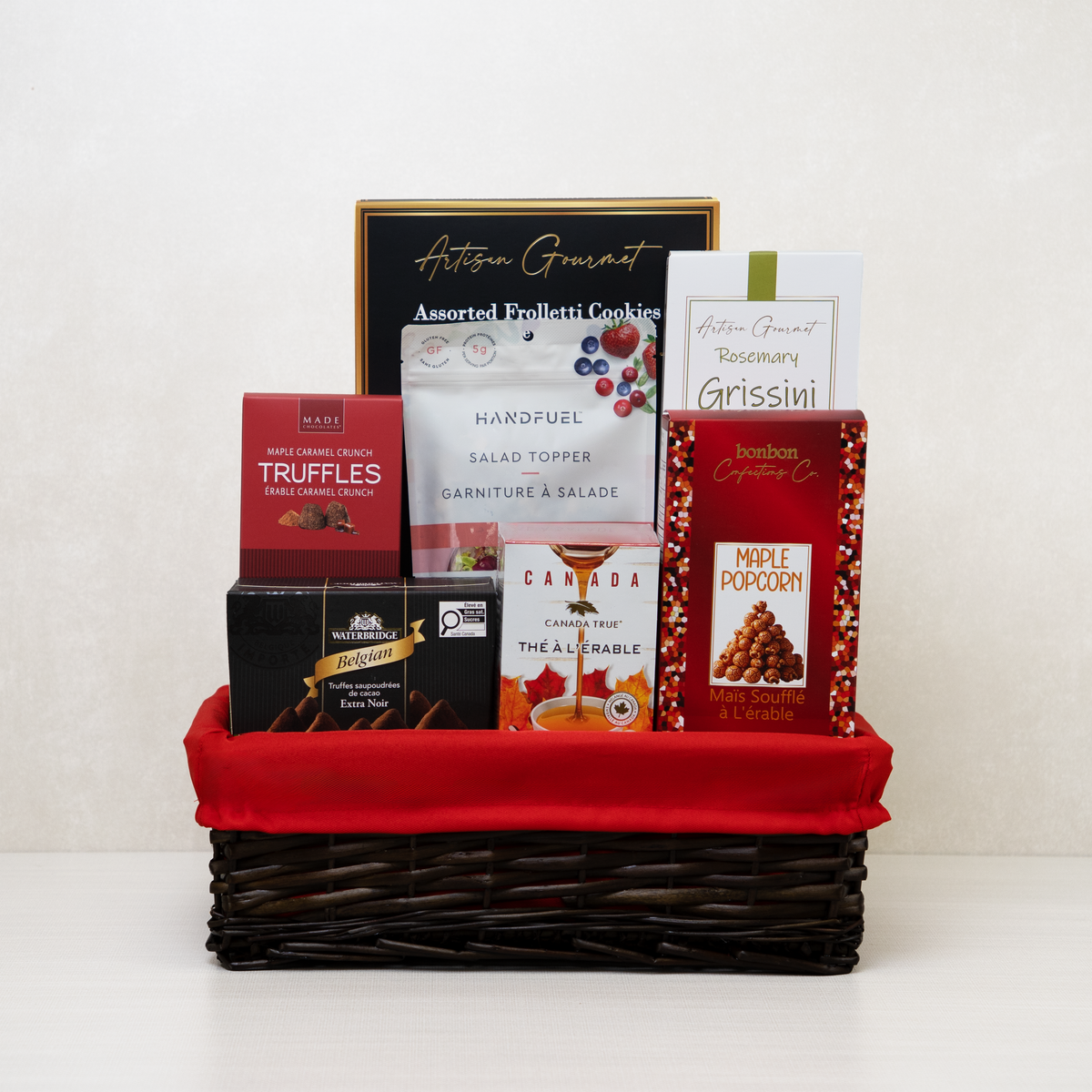 Merry & Gourmet Gift Basket with maple popcorn, maple tea, maple caramel truffles and rosemary grissini in red-lined wicker