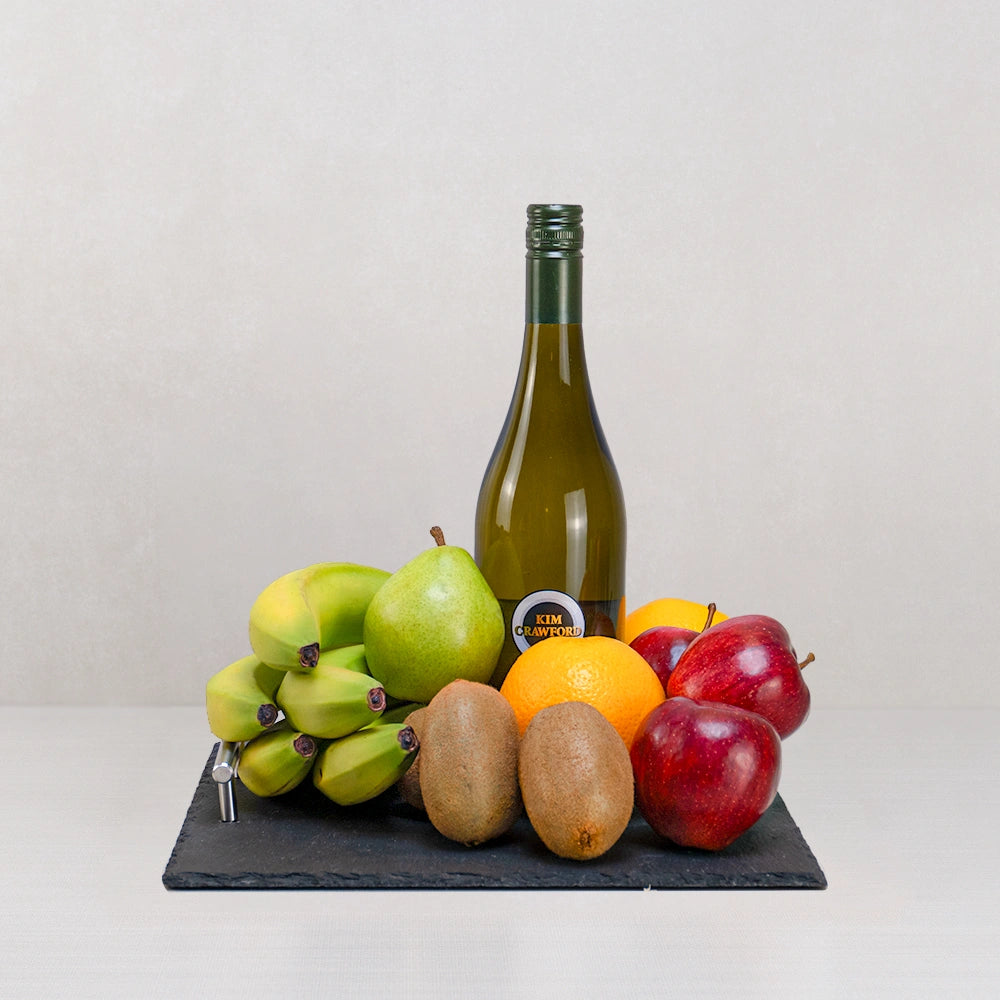 Bright Days Ahead Wellness Basket with Kim Crawford white wine, bananas, a pear, kiwis, an orange and apples on a slate tray