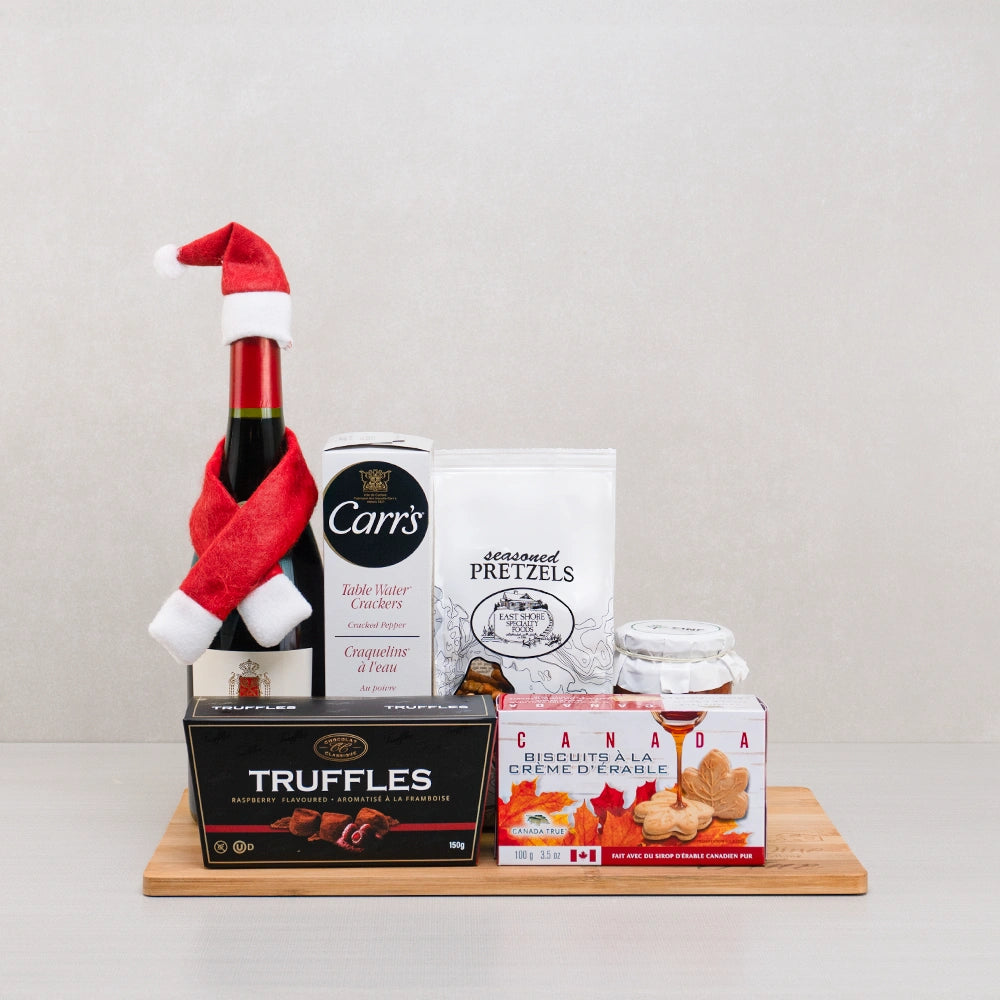 Wine, Pretzels & Maple Treats gift set with red wine in a Santa hat and scarf, seasoned pretzels and maple cream cookies