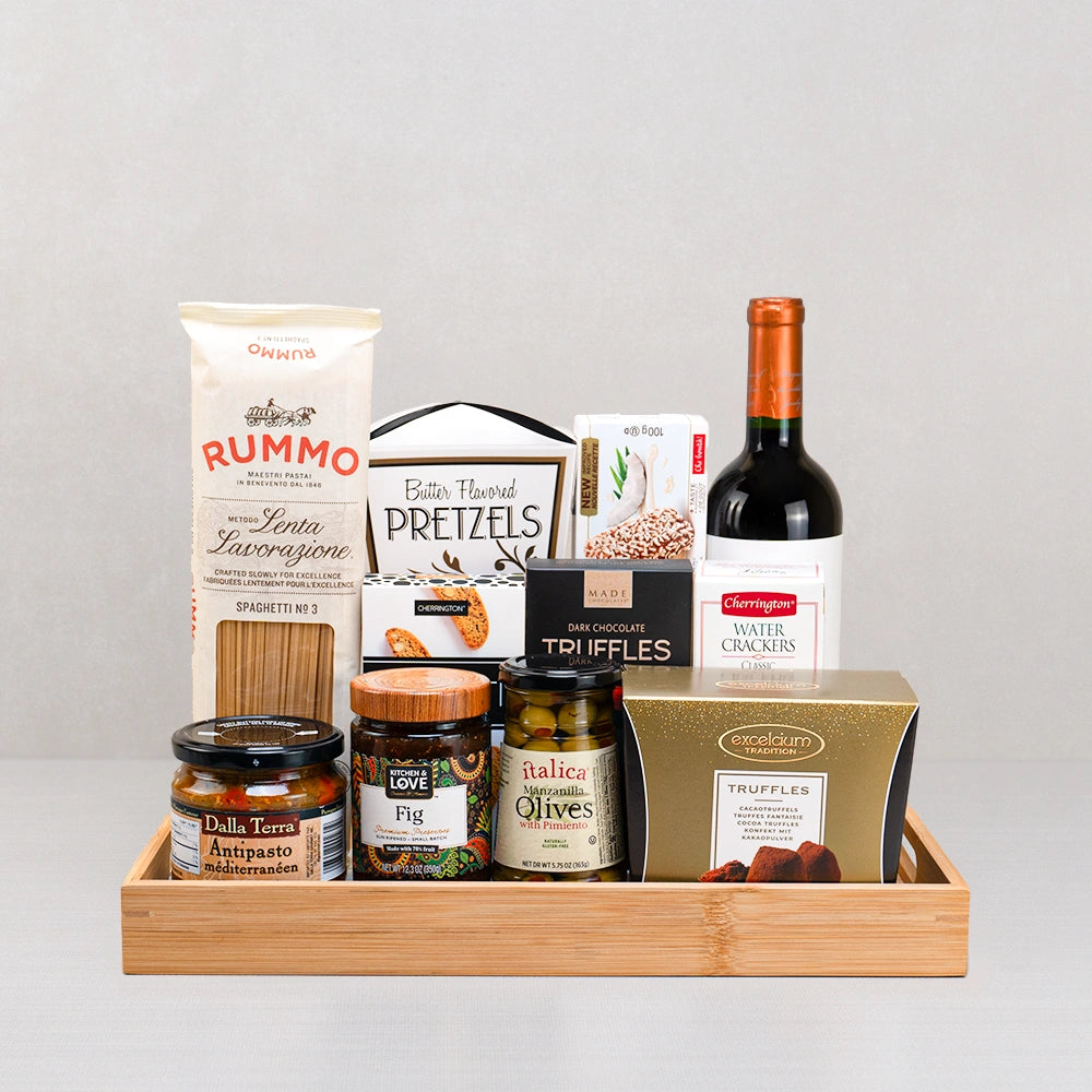 The Fine Taste of Italy Gift Basket with red wine, Rummo spaghetti, olives, fig preserve and antipasto on a bamboo tray