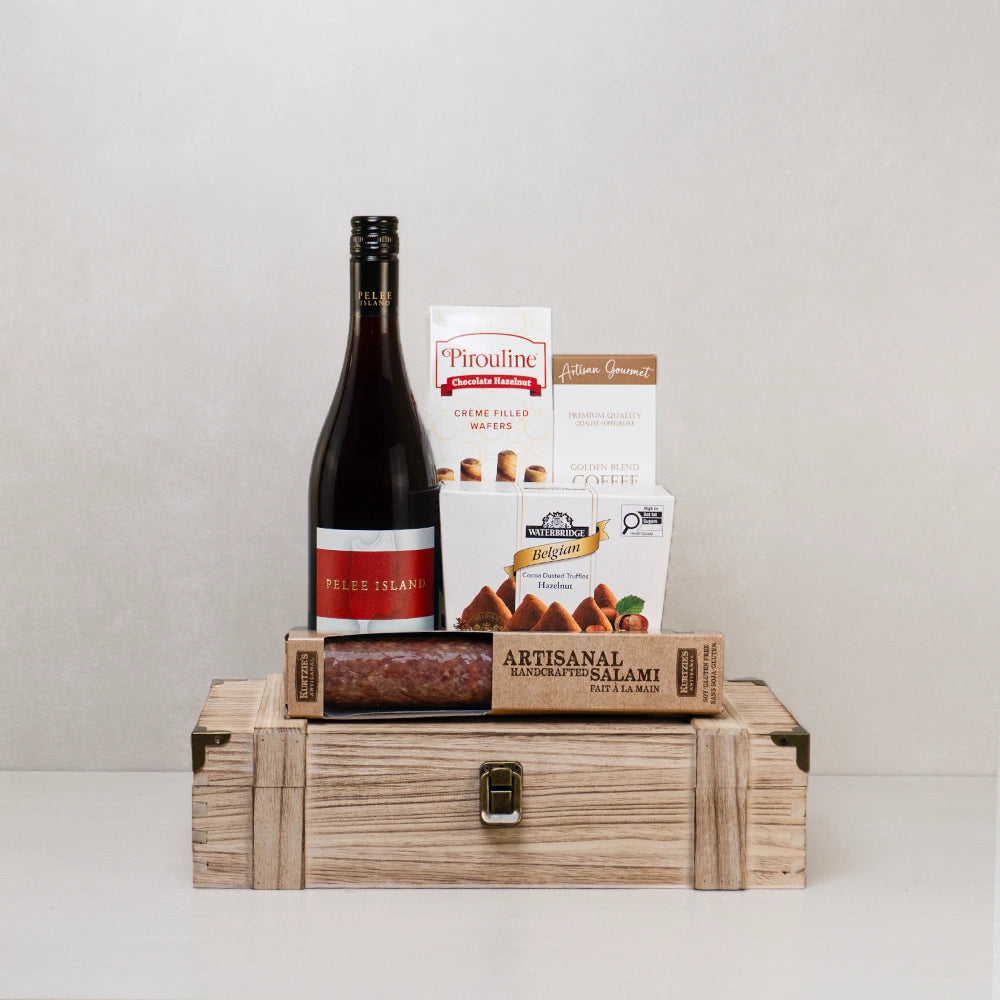 Red wine gift basket with truffles, wafers, artisanal salami, and coffee in a rustic wooden box.