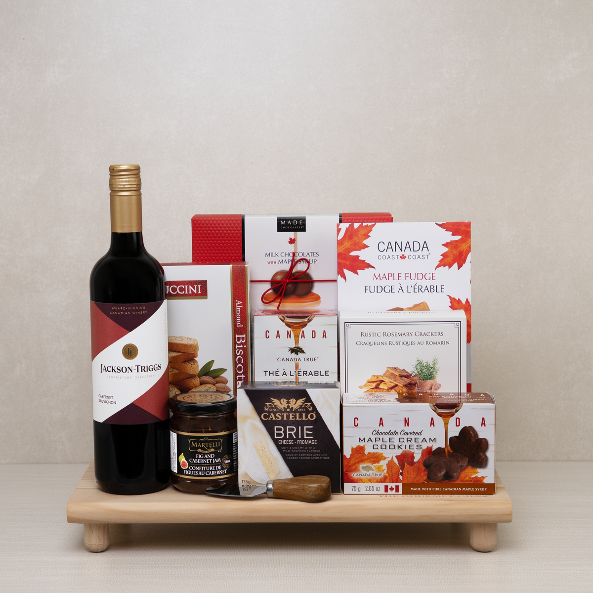 Wine & Maple Treats Gift Set with wine, crackers, jam, chocolates, crackers and more on a bamboo tray.